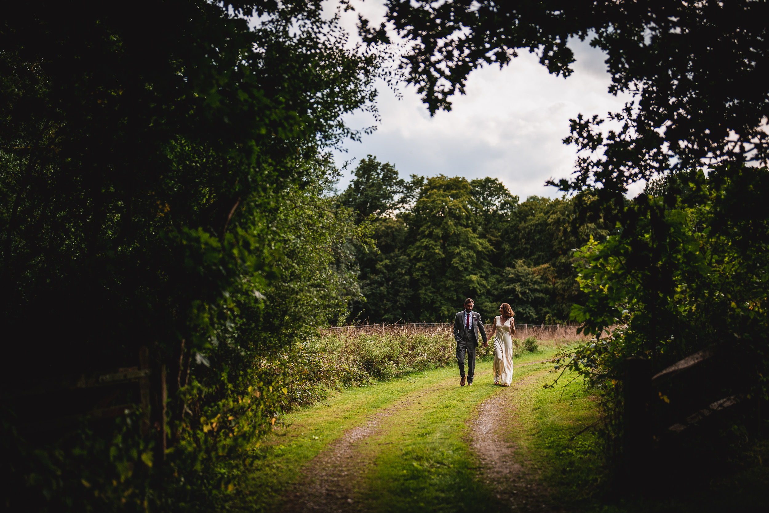 A Surrey wedding couple taking a romantic stroll through the enchanting woods of Ridge Farm.