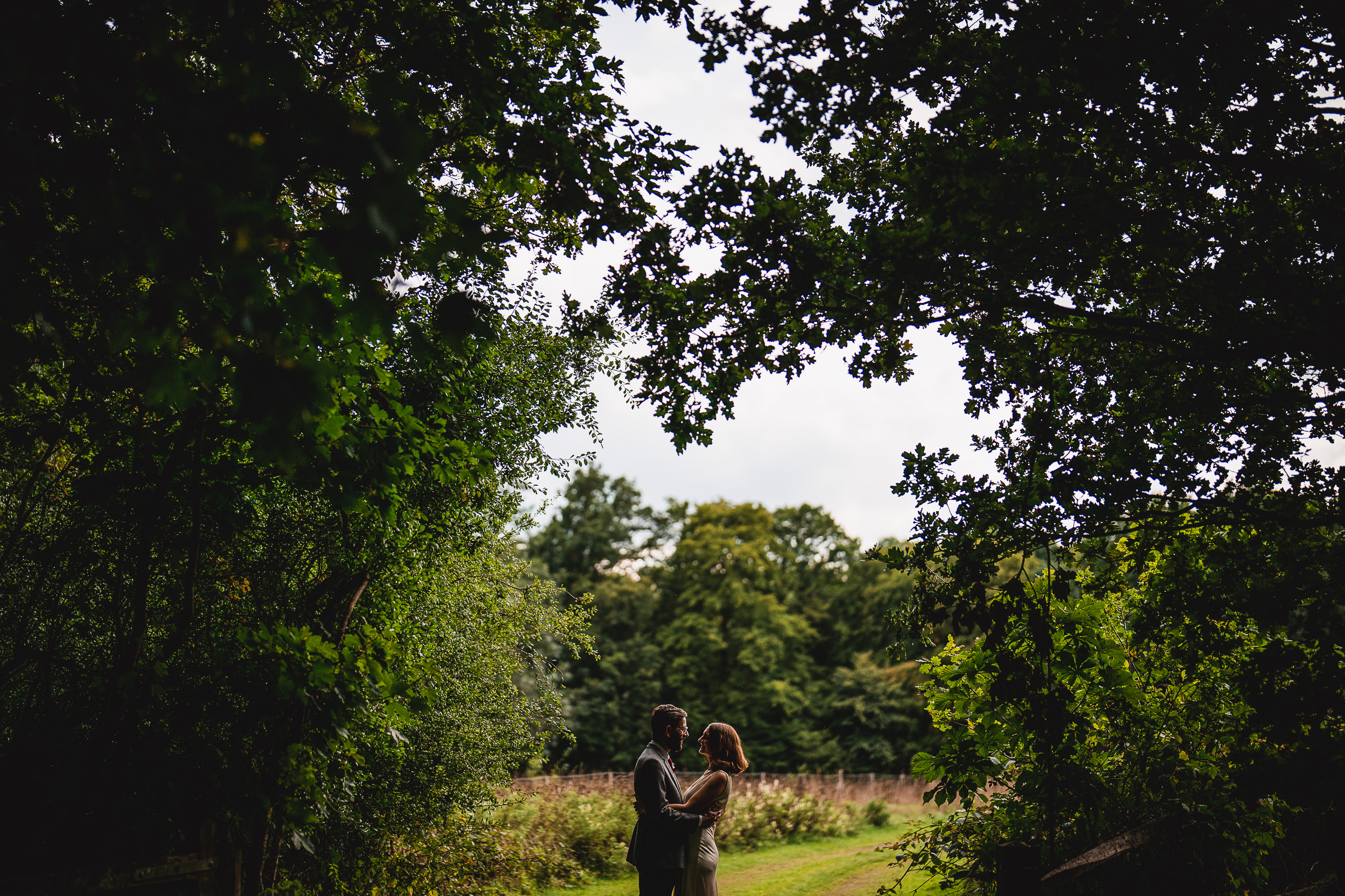 Ridge Farm Weddings. A bride and groom posing elegantly amidst the tranquility of a secluded clearing in the woods.