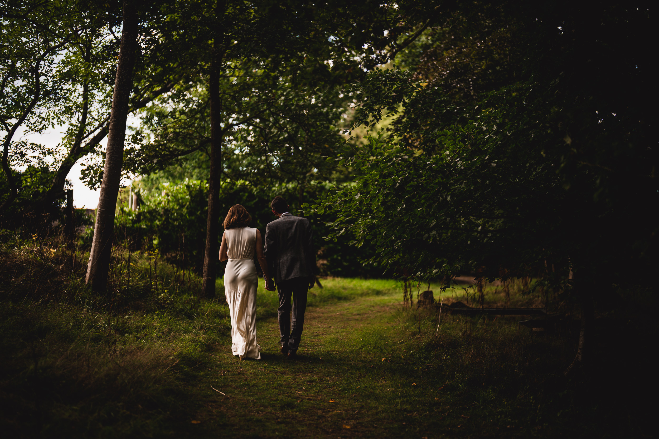 A Ridge Farm wedding: A bride and groom walking down a path in the woods.
