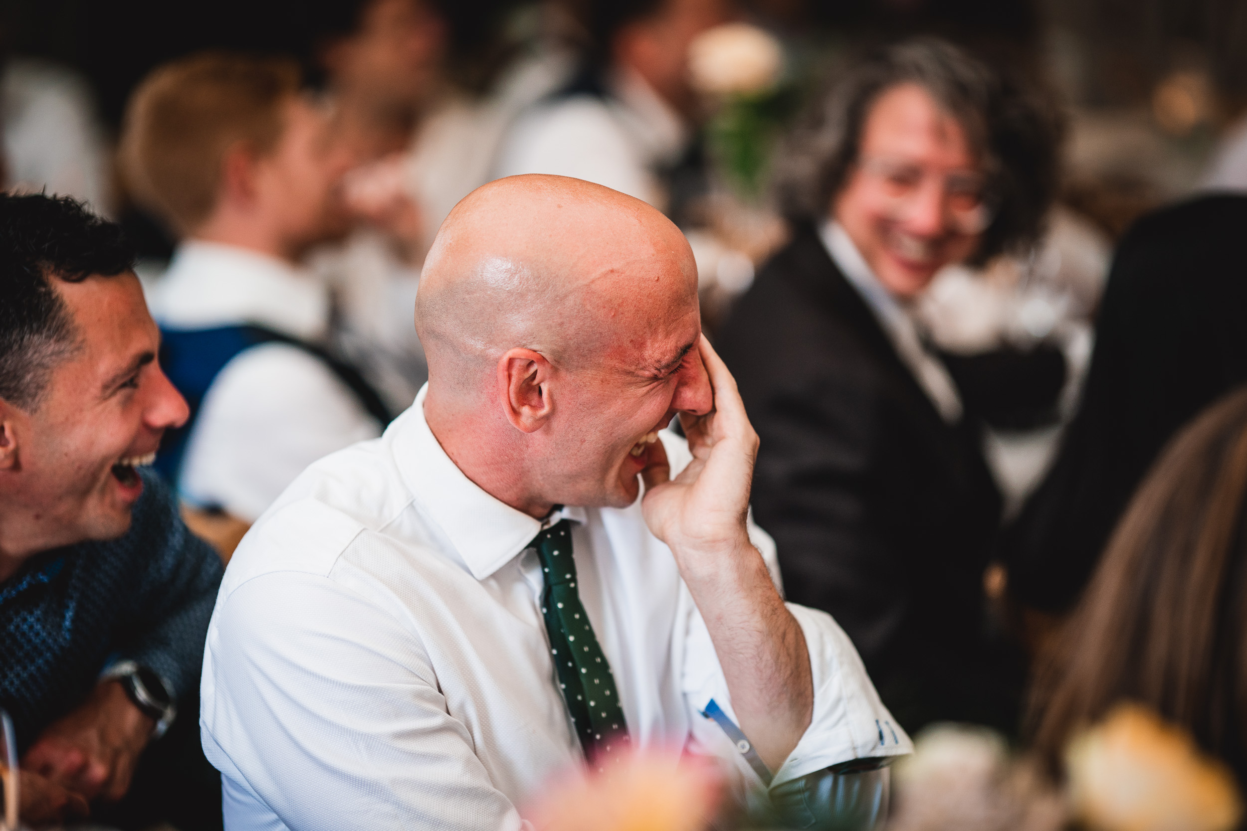 A man laughing at a Surrey wedding reception.