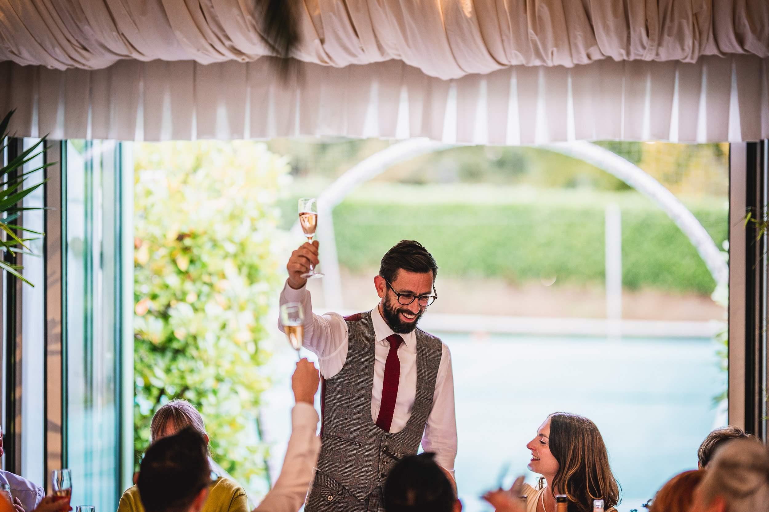 A man holding a glass of wine at a Surrey wedding reception.