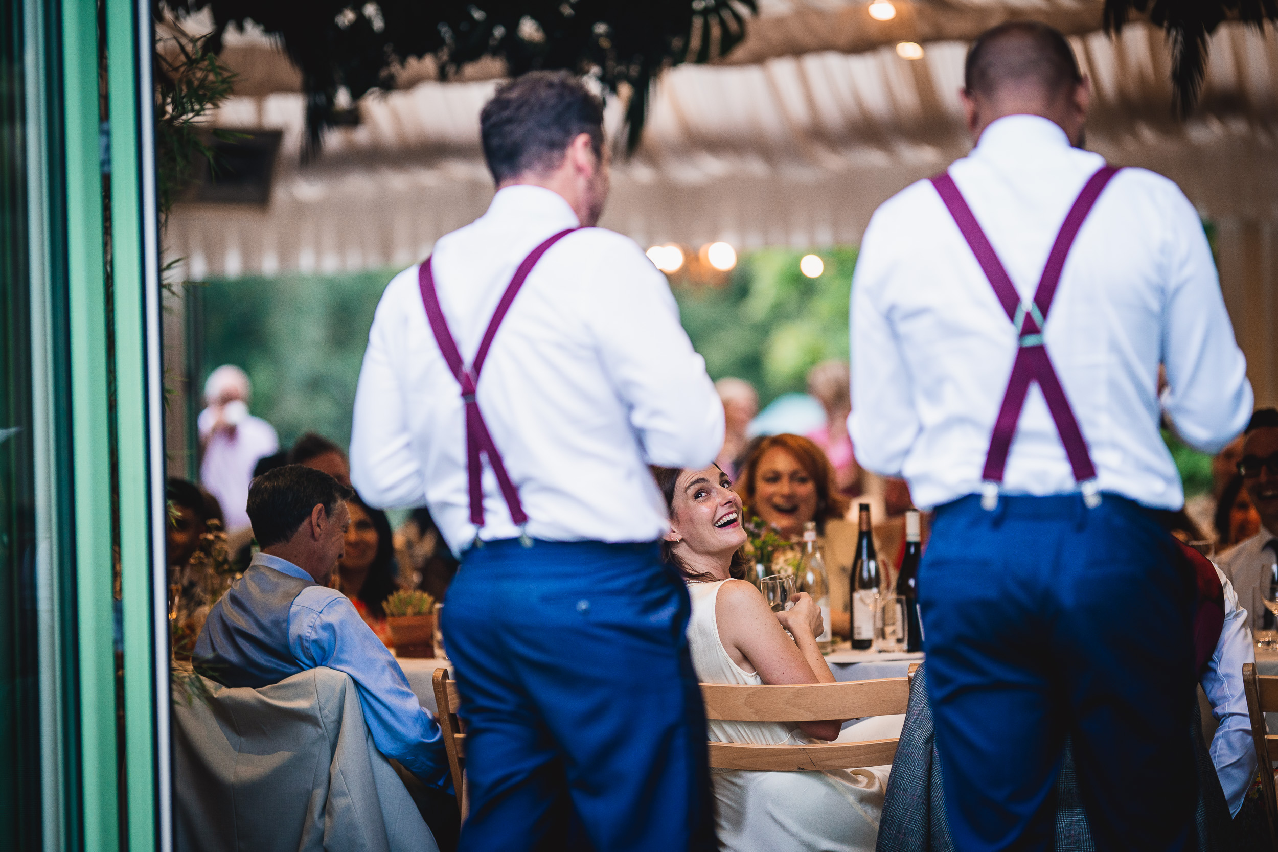 Two men in suspenders standing at a Surrey wedding reception.