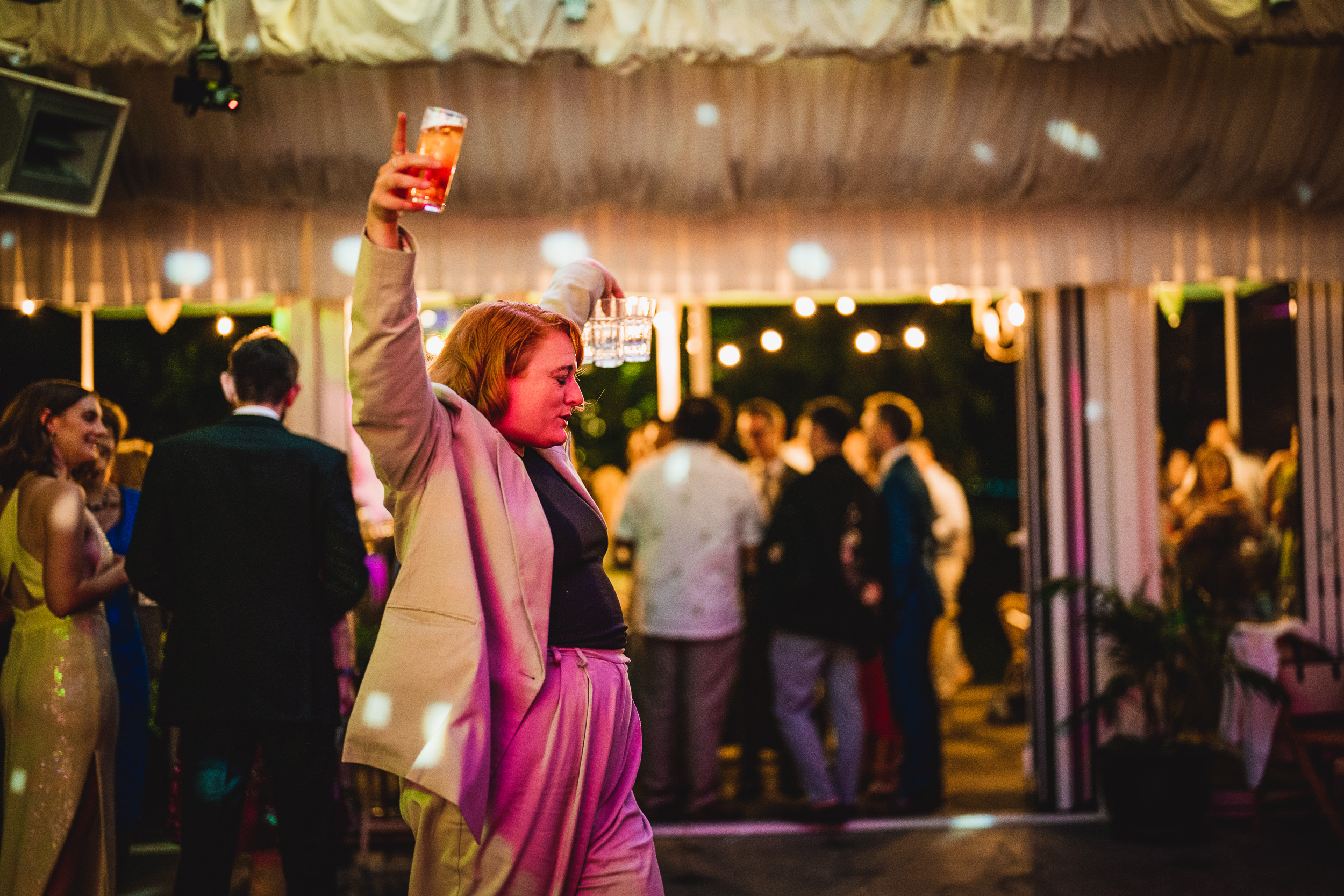 A woman holding up a drink at a Surrey Wedding party.